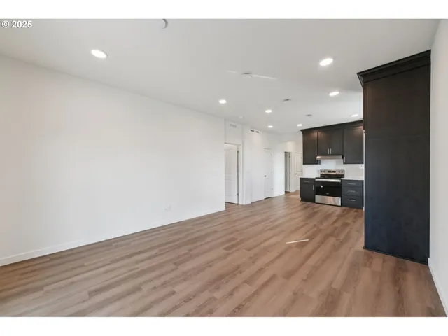 a view of kitchen and empty room with wooden floor