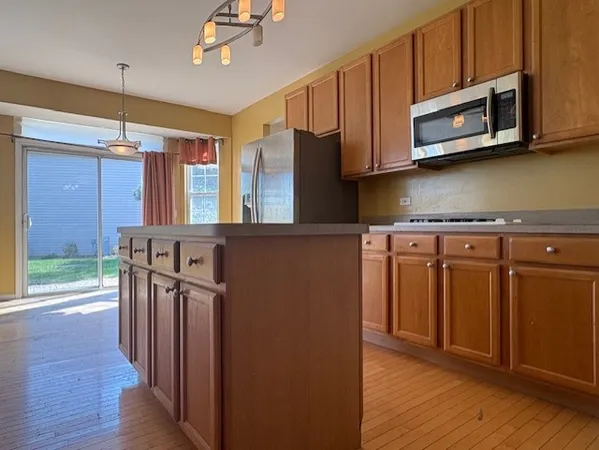 a kitchen with stainless steel appliances granite countertop a refrigerator a stove top oven a sink and dishwasher with wooden floor