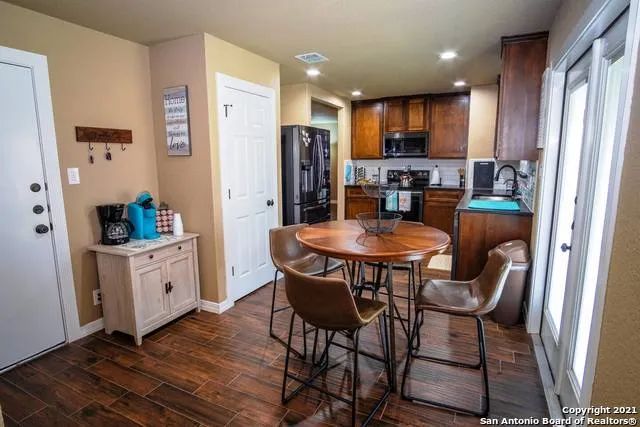 a kitchen with stainless steel appliances kitchen island granite countertop a refrigerator a stove a sink a dining table and chairs with wooden floor