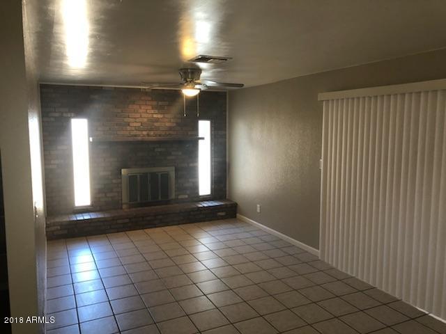 4008 West Davidson Lane Phoenix, AZ 85051 - Photo 4 of 12 an empty room with fireplace and windows