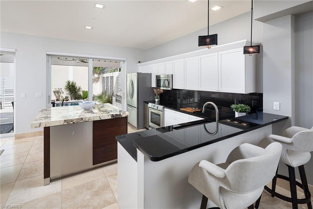 1070 5th Street South Naples, FL 34102 - Photo 5 of 23 a kitchen with stainless steel appliances kitchen island granite countertop a sink and chairs