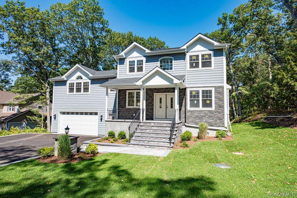 597 Pulaski Road Kings Park, NY 11754 - Photo 1 of 1 View of front of property featuring driveway, covered porch, stone siding, a garage, and a front lawn