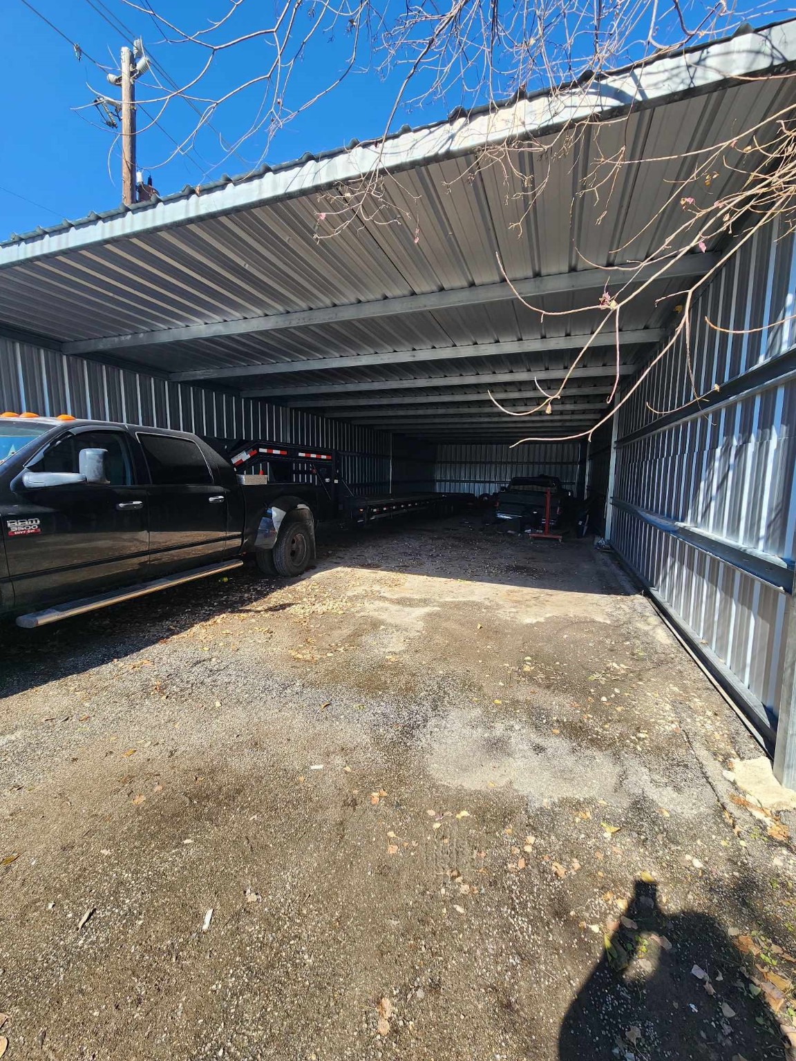 0 Rasmus Drive Houston, TX 77063 - Photo 7 of 11 This photo shows a large, open metal carport with ample space for multiple vehicles, featuring a gravel floor and partial enclosure on three sides.