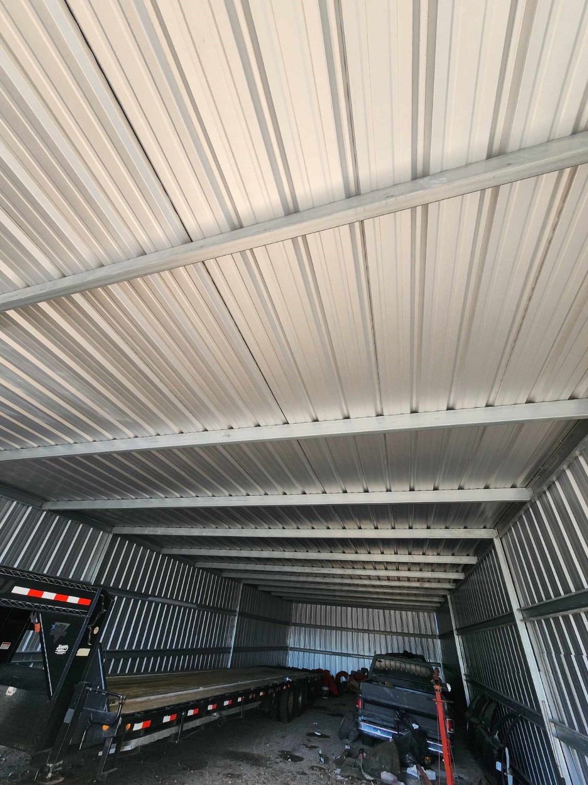 0 Rasmus Drive Houston, TX 77063 - Photo 8 of 11 The photo shows a spacious metal storage unit or garage with a corrugated metal roof and walls. Inside, there is a large trailer and some equipment, indicating ample space for storage or vehicle parking.