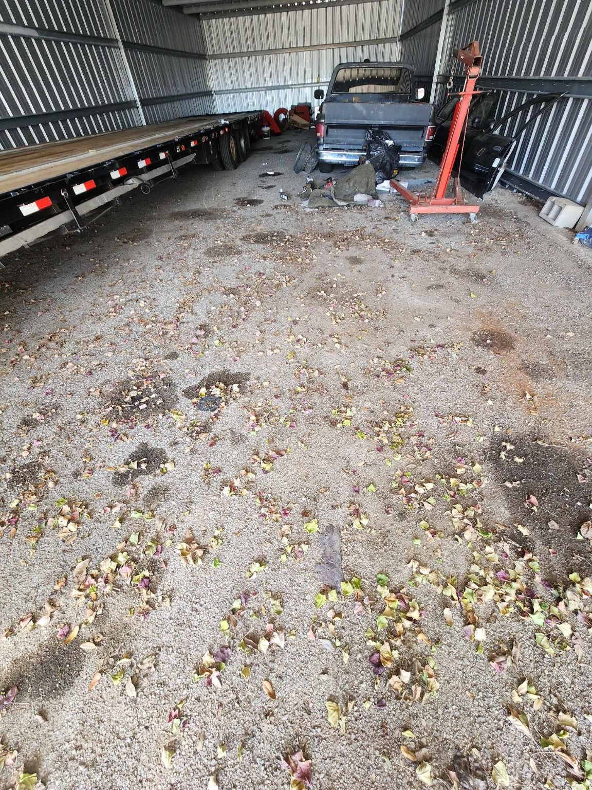 0 Rasmus Drive Houston, TX 77063 - Photo 9 of 11 This photo shows a spacious metal storage unit or garage with gravel flooring. It's currently used to store a truck, trailer, and various equipment, with some scattered leaves and debris on the ground. Ideal for vehicle or equipment storage.
