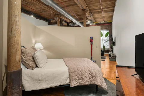 a bedroom with a bed a couch and wooden floor