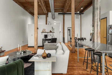 a living room with furniture kitchen view and a wooden floor