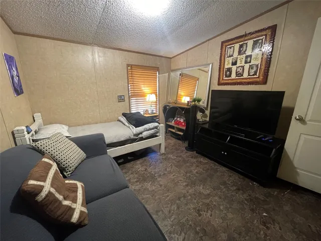 a bedroom with bed and a flat tv screen on dresser