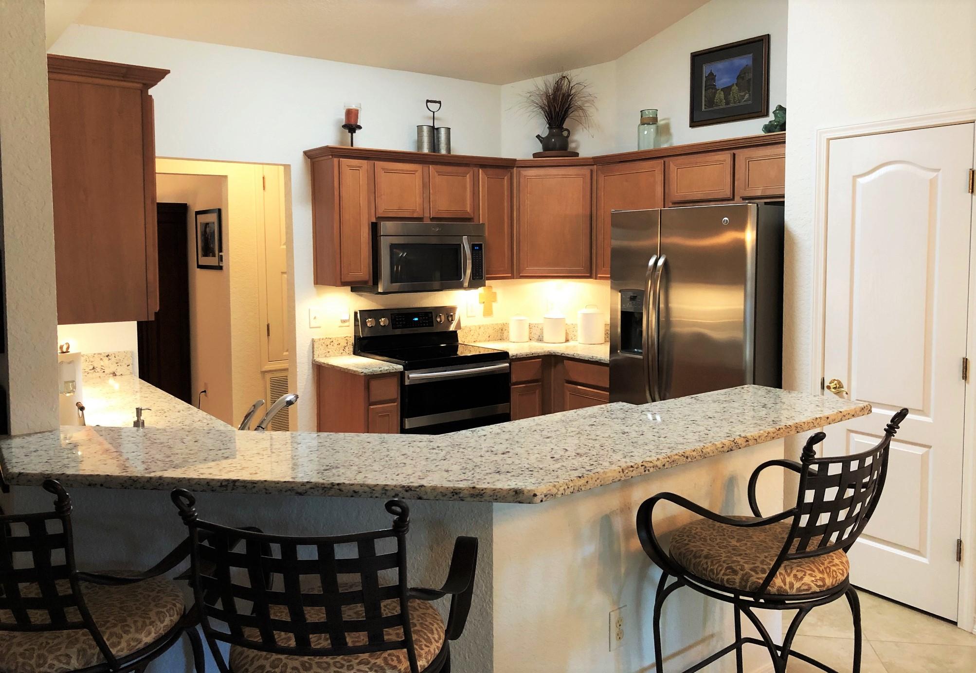 44 East Shipwreck Road Santa Rosa Beach, FL 32459 - Photo 18 of 33 a kitchen with granite countertop a table chairs microwave and refrigerator