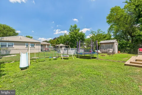 a view of backyard with table and chairs and potted plants and large trees