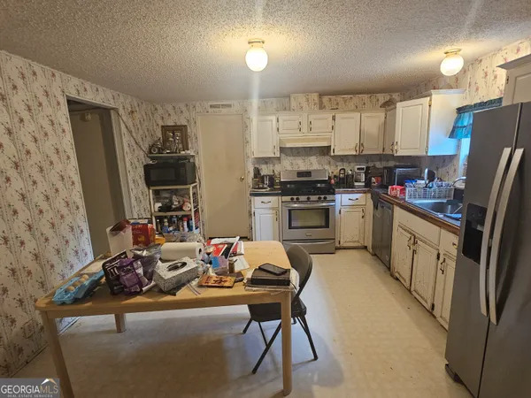 a kitchen with stainless steel appliances kitchen island granite countertop a refrigerator a stove a sink dishwasher and white cabinets with wooden floor