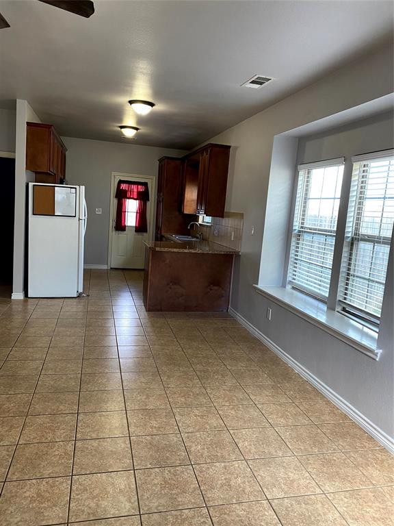 906 Parkplace Ridge Princeton, TX 75407 - Photo 20 of 31 Open-concept kitchen and dining area featuring tile flooring, dark wood cabinetry, a built-in breakfast bar, and multiple windows with blinds