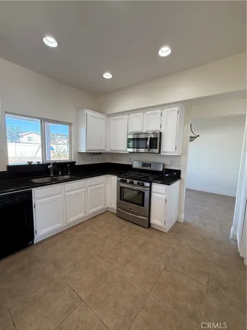 a large kitchen with cabinets a sink and white appliances