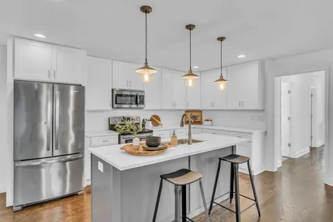 a kitchen with a refrigerator a sink and chairs