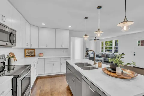 a kitchen with kitchen island granite countertop a sink a counter space appliances and cabinets