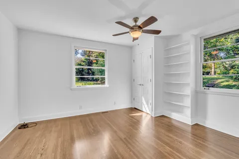 a view of an empty room with a window and wooden floor