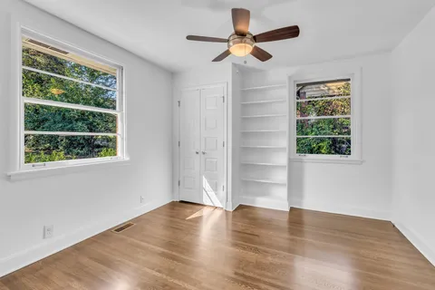 a view of an empty room with a window and wooden floor