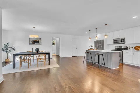 a kitchen with kitchen island a stove a refrigerator a dining table and chairs with wooden floor