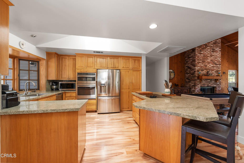 4850 North Moorpark Road Thousand Oaks, CA 91360 - Photo 12 of 54 a kitchen with stainless steel appliances granite countertop a stove a refrigerator a sink a dining table and chairs with wooden floor