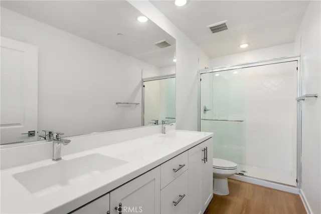 a bathroom with a sink toilet double vanity and shower