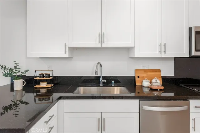 a kitchen with granite countertop white cabinets and a stove