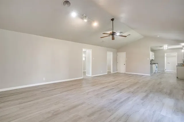 a view of a livingroom with a chandelier fan and wooden floor