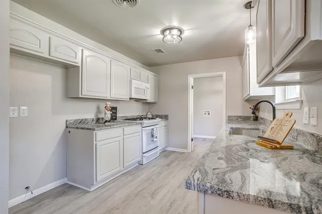 a large kitchen with a sink stainless steel appliances and cabinets