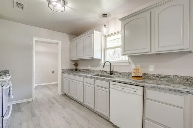 a kitchen with granite countertop white cabinets and white appliances