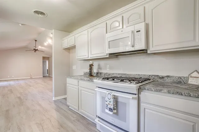 a kitchen with stainless steel appliances granite countertop a stove a sink and white cabinets