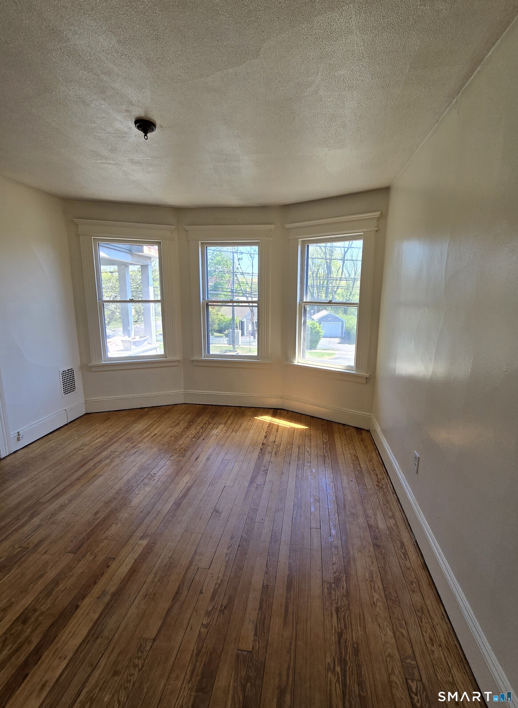 985 Huntington Road Stratford, CT 06614 - Photo 2 of 7 an empty room with wooden floor and windows
