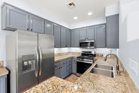 a kitchen with granite countertop a refrigerator sink and stove