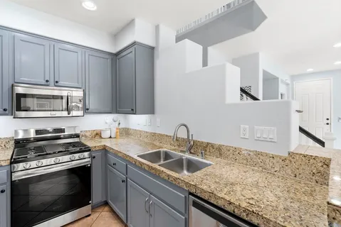 a kitchen with granite countertop a sink stainless steel appliances and cabinets
