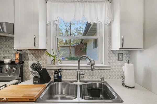 a kitchen with stainless steel appliances granite countertop a stove a sink and a white cabinets