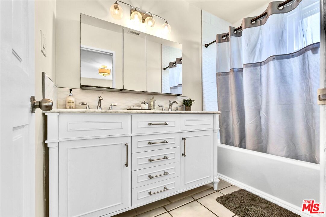 11670 Sunset Boulevard, Unit 303 Los Angeles, CA 90049 - Photo 18 of 32 a bathroom with a sink a mirror a vanity and a shower