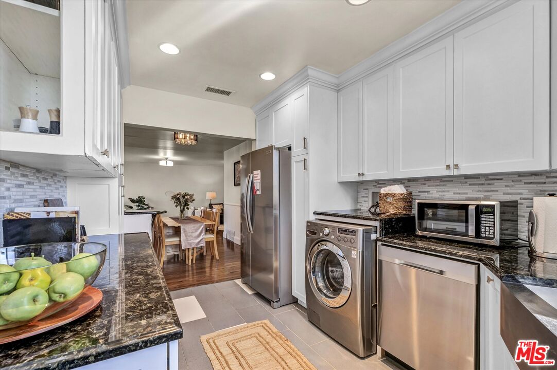 11670 Sunset Boulevard, Unit 303 Los Angeles, CA 90049 - Photo 6 of 32 a kitchen with stainless steel appliances granite countertop a stove a refrigerator a sink a table and chairs