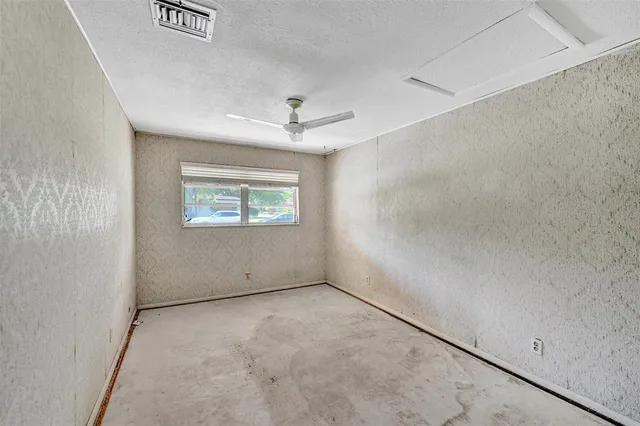 an empty room with windows and chandelier fan