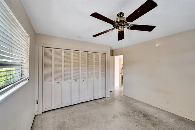 an empty room with ceiling fan and window