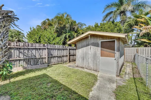 a view of backyard with wooden fence and large trees