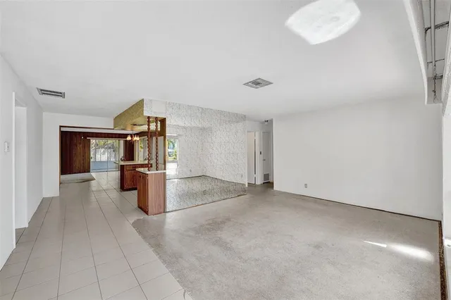 an empty room with kitchen view and a window