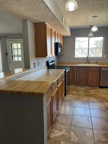 a large kitchen with kitchen island granite countertop a sink a counter top space and cabinets