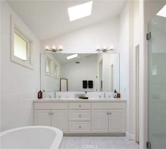 a bathroom with a double vanity sink mirror and bathtub