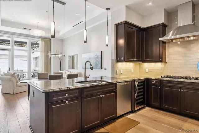 a kitchen with stainless steel appliances granite countertop a sink dishwasher stove and refrigerator with wooden floor