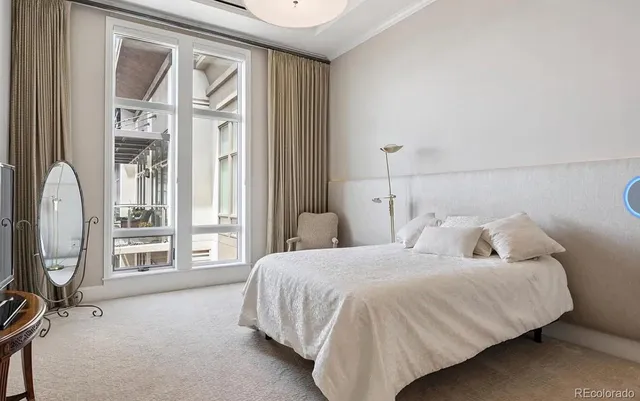 a bedroom with a bed a mirror and a large window