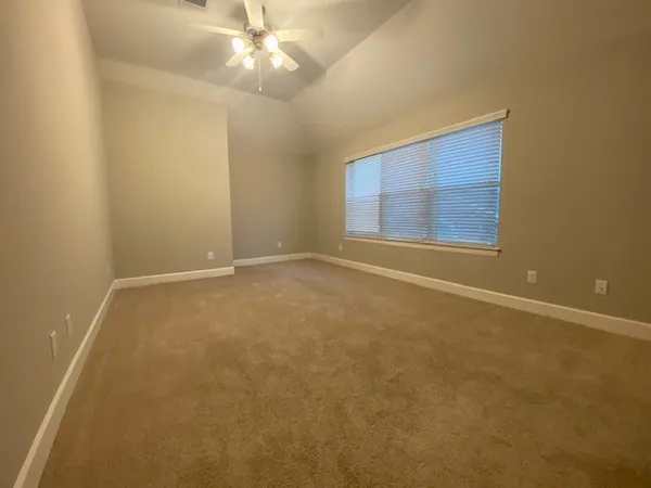 an empty room with a ceiling fan and a window