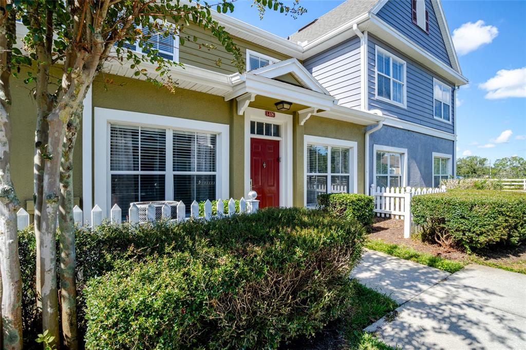 front view of a brick house with a large window plants and palm trees