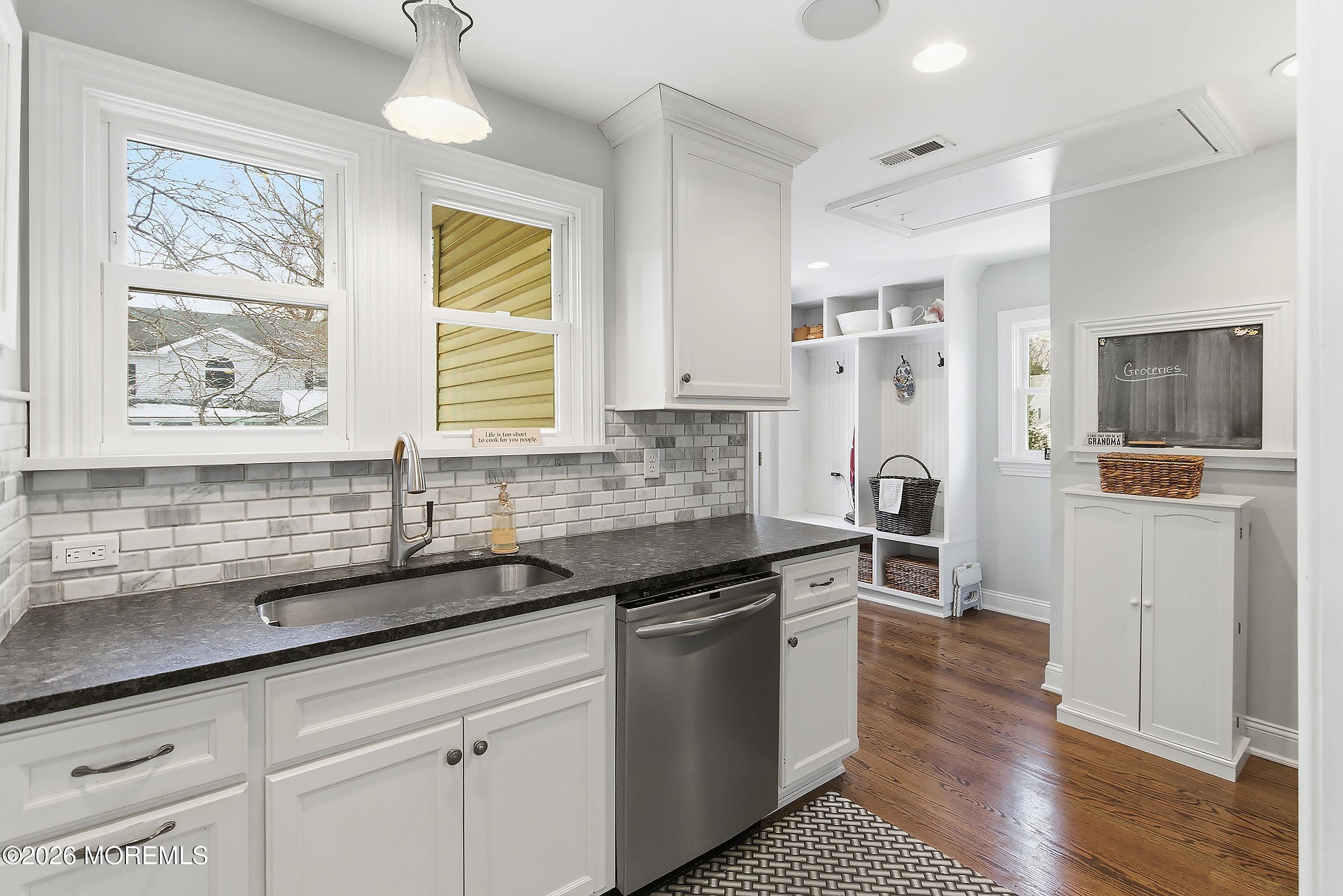 a kitchen with granite countertop a sink cabinets stainless steel appliances and a window
