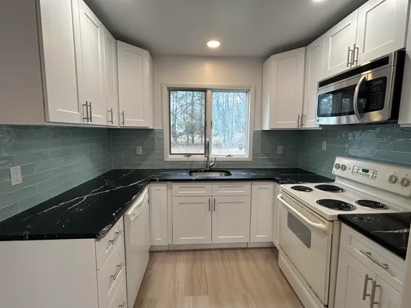 a kitchen with stainless steel appliances granite countertop white cabinets a sink and a stove