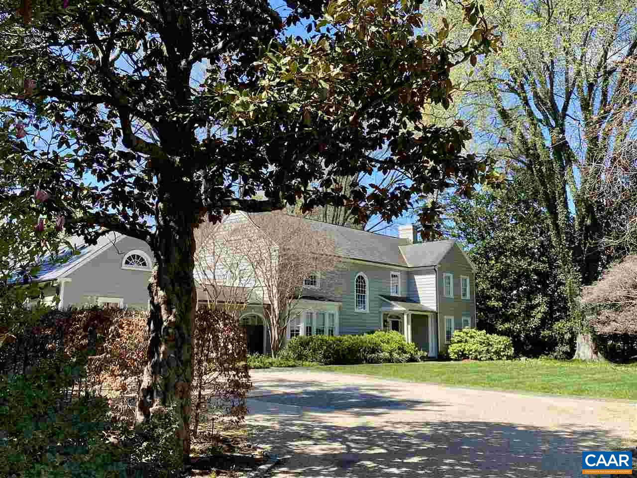 a view of a white house next to a yard with big trees
