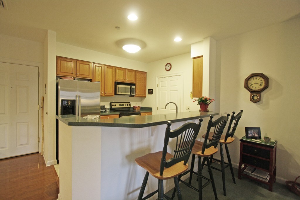 190 Chickering, Unit 210D North Andover, MA 01845 - Photo 4 of 16 a kitchen with stainless steel appliances granite countertop a table and chairs in it