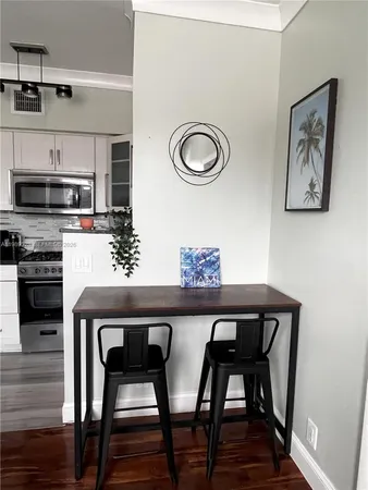 a kitchen with stainless steel appliances granite countertop a table chairs stove and white cabinets